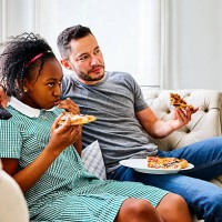 father and daughter eating pizza and watching tv - junk food stockfoto's en -beelden