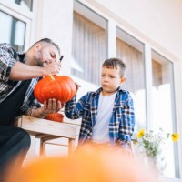 father and son drawing jack on pumpkin for halloween in the back yard of house - garden decoration stock pictures, royalty-free photos & images