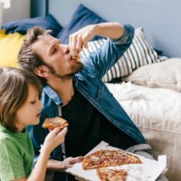 father and son eating pizza at home - junk food stock pictures, royalty-free photos & images
