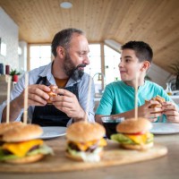 father and son eating slider - burgers at home - junk food stock pictures, royalty-free photos & images