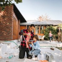 father and son using digital tablet while mother talking to daughter outside house - home decoration stock pictures, royalty-free photos & images