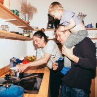 father carrying son on shoulder by woman cooking food in kitchen at home - food stock pictures, royalty-free photos & images