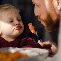 father feeding his little son with tasty pasta - food stockfoto's en -beelden