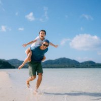 father giving piggyback ride to young daughter on beach, japan - travel stock-fotos und bilder