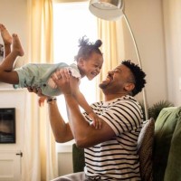 father lifting toddler daughter in the air - home decoration photos et images de collection