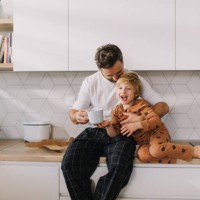 father sitting on kitchen counter with his little son and having morning coffee. - food stock pictures, royalty-free photos & images