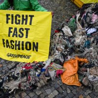 February 2024, Berlin: Greenpeace activists protest at the Brandenburg Gate against the pollution of the environment in Ghana caused by fast fashion...