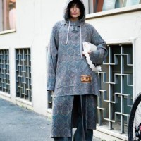 Federica Messaggeri wears beige suede ankle boots, an oversized jacquard lilac and beige hoodie, light greenish denim wide leg trousers and a white...