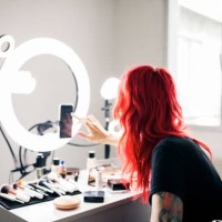 female artist with dyed red hair using smart phone while vlogging at studio - fashion stock pictures, royalty-free photos & images