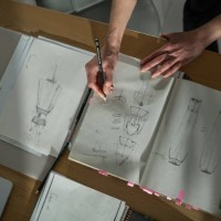 female atelier sitting at table in studio and drawing new fashion models - fashion stock pictures, royalty-free photos & images