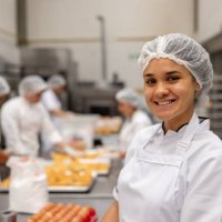 female baker working at an industrial bakery and smiling - food stock pictures, royalty-free photos & images
