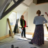 female builder in an attic building site stands with another builder and the client discussing the project. they stand in the attic / roof space with exposed roof beams - home decoration stock pictures, royalty-free photos 