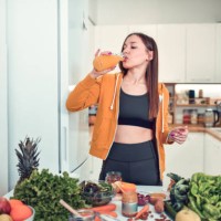 female drinking smoothie to start healthy nutrition while preparing main course at home - food stock pictures, royalty-free photos & images