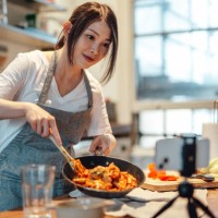 female food blogger cooking pasta and recording video on smart phone - food stockfoto's en -beelden