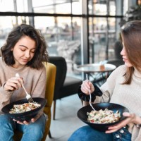 female friends enjoying healthy salad meal in restaurant - junk food stock pictures, royalty-free photos & images