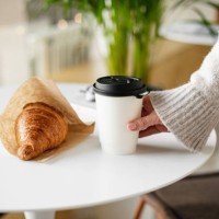 female hand holding a disposable glass with coffee and fresh croissant. concept of delivery food - junk food stock pictures, royalty-free photos & images