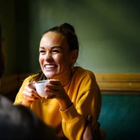 female laughing with friend while drinking coffee - coffee stockfoto's en -beelden