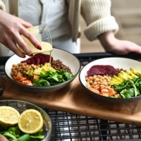 female preparing aesthetically pleasing salad bowls adding dressing on top to tie flavors together - food stock pictures, royalty-free photos & images