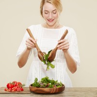 female smiling as she tosses a fresh salad - food stock pictures, royalty-free photos & images