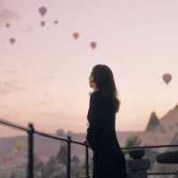 female tourist enjoying watching hot air balloons flying in the sky at rooftop of hotel where she is staying during her vacation - travel stock pictures, royalty-free photos & images