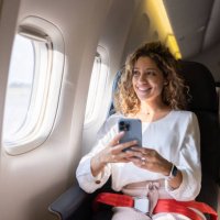 female traveler using her cell phone in an airplane - travel stock pictures, royalty-free photos & images
