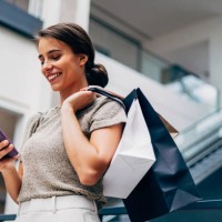 femme heureuse faisant du shopping et utilisant un smartphone dans un centre commercial moderne - fashion photos et images de collection
