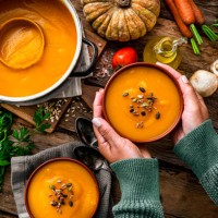 femme tenant un bol de soupe à la citrouille pour le repas de thanksgiving - food photos et images de collection