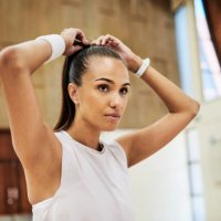 fit young woman tying her hair while getting ready for exercising and training in a sport center or gym. one determined and dedicated athlete looking focused and prepared for a workout or competition - hairstyle stock picture