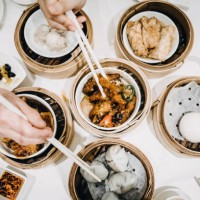 flat lay chinese dim sum time, various traditional dim sum freshly served on table and human hands picking up with chopsticks - junk food stockfoto's en -beelden