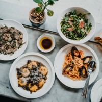 flat lay of meal for two people with fresh green salad, appetizer, seafood linguine and beef ravioli freshly served on dining table in a restaurant - food stock pictures, royalty-free photos & images