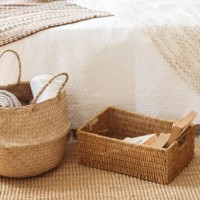 folded gray knitted plaid in straw basket on wicker carpet near bed. cozy hygge home style. fall winter season concept. close up, copy space. - home decoration stockfoto's en -beelden
