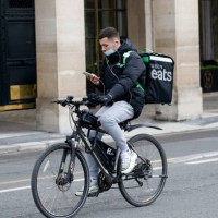 Food deliverer for Uber Eats checks his GPS as he rides his bicycle during the coronavirus outbreak on February 17 in Paris, France. With the closure...