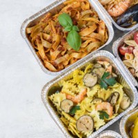 food delivery. different aluminium lunch box with healthy natural chinese food dumplings, noodles with chicken, rice with chicken, pasta with salmon, falafel. airlines food. airline meals and snacks. takeaway food. - junk fo