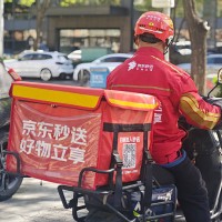 Food delivery rider of JD Takeaway, the food delivery service under China's e-commerce giant JD.com, rides an electric bicycle along a road on April...