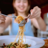 fröhliche frau, die würzige spaghetti im restaurant isst. - food stock-fotos und bilder