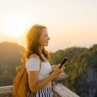 frau mit smartphone auf dem gipfel des wat tham sua in krabi bei sonnenuntergang - travel stock-fotos und bilder