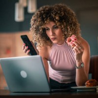 freelancer woman eating breakfast while working at laptop from home - junk food stock pictures, royalty-free photos & images