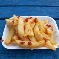 Fried chips or fries with tomato ketchup on.