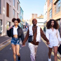 friends confidently walking along a city street in bright sunlight - fashion stock pictures, royalty-free photos & images