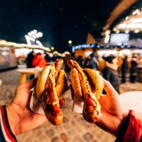 friends eating bratwurst sausage with mustard and ketchup at christmas market in berlin, germany - junk food stock pictures, royalty-free photos & images