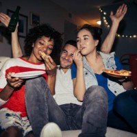 friends eating pizza on sofa during party at home - junk food stock pictures, royalty-free photos & images