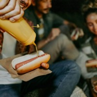 friends enjoying hot dogs while camping outdoors - junk food stock pictures, royalty-free photos & images