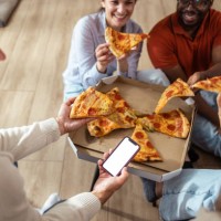 friends enjoying pizza together at home with smartphone interaction - phone with white screen - junk food stock pictures, royalty-free photos & images
