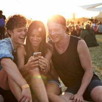 friends laughing, while looking at smartphone - concert stock-fotos und bilder
