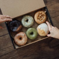 friends sharing a box of delicious crafted donuts - junk food stock pictures, royalty-free photos & images