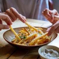 friends sharing and enjoying fries topped with parmesan cheese and truffled mayonnaise sauce. - food stock pictures, royalty-free photos & images