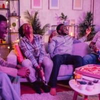 friends sitting together playing video games at home - junk food stock pictures, royalty-free photos & images