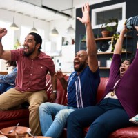 friends watching tv at home and cheering with arms raised - junk food stock pictures, royalty-free photos & images