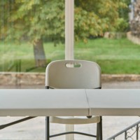 front view of an indoor white plastic chair and table and some grass outside of home. plastic chair and table inside of a home. - garden decoration stock pictures, royalty-free photos & images