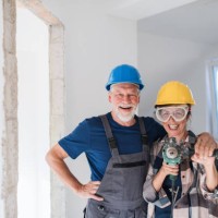 front view portrait of senior couple workers with drill in new home. - home decoration stock pictures, royalty-free photos & images
